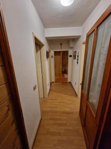 ein leerer Flur mit einer Tür und einem Kreuz an der Wand in der Unterkunft Appartamento Lorena in Rocca Pietore