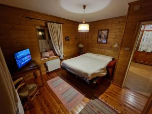 ein Schlafzimmer mit einem Bett und einem Schreibtisch mit einem Fernseher in der Unterkunft Appartamento Lorena in Rocca Pietore