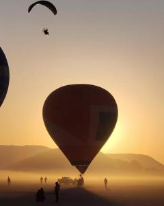 een groep mensen die bij zonsondergang een luchtballon laat vliegen bij Wadi Rum Karolina Bubbles camp in Wadi Rum