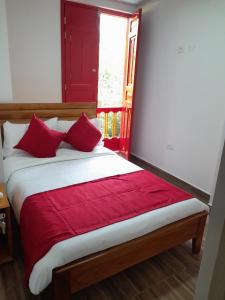 a bed with red pillows in a room with a window at La Casa De Mi Tatis in Salento