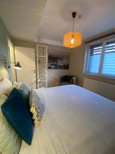 een slaapkamer met een groot wit bed met een kroonluchter bij Appartement rez Terrasse et Jardin in Huy