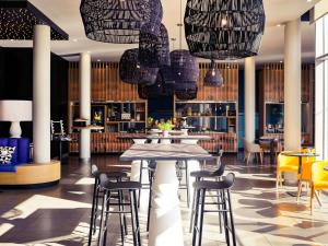 热纳里昂热纳欧洲博览中心美居酒店的餐厅设有桌椅和吊灯。