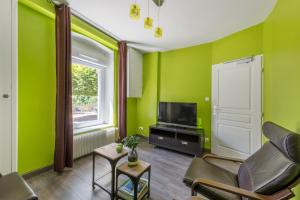 a living room with green walls and a television at Hôtel De La Plage in Le Chambon-sur-Lignon