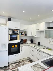 een keuken met witte kasten en een zwarte oven bij Villa Josèphe in Capbreton