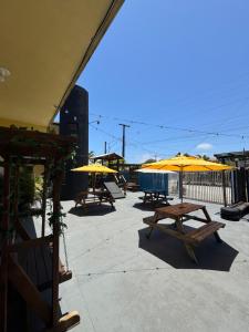een groep picknicktafels met gele parasols bij Hostel Farol in Pontal do Paraná