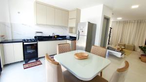 a kitchen with a white table and chairs and a white refrigerator at Mansão dos Mares 06 in Ilhéus