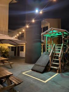 een patio met een tafel, banken en verlichting bij Hostel Farol in Pontal do Paraná