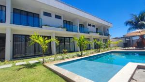 a villa with a swimming pool in front of a building at Mansão dos Mares 06 in Ilhéus