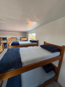 een slaapkamer met drie bedden en een raam bij Hostel Farol in Pontal do Paraná