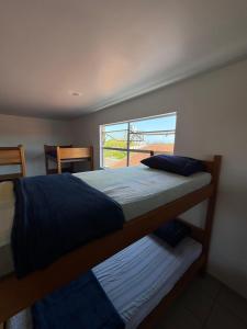 twee stapelbedden in een kamer met een raam bij Hostel Farol in Pontal do Paraná