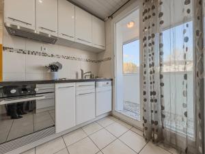 une cuisine avec des placards blancs et une grande fenêtre dans l'établissement Le 19 Lavigne - Parking, à Saint-Martin-dʼHères