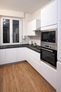 a kitchen with white cabinets and black appliances at Easy Room Italy Central Station in Milan
