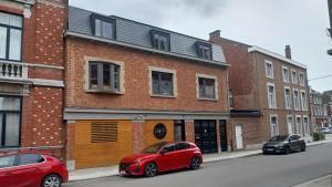 een rode auto geparkeerd voor een bakstenen gebouw bij Appartement rez Terrasse et Jardin in Huy