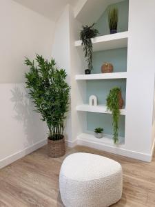 una stanza con scaffali bianchi con piante e un pouf bianco di La Jungle - T2 à Melesse a Melesse