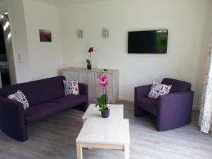 a living room with two purple couches and a coffee table at Dunopark Villa in Oostkapelle