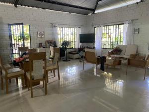 een woonkamer met stoelen, tafels en ramen bij El Paraíso in Rivera
