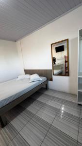 ein Schlafzimmer mit einem Bett und einem Spiegel an der Wand in der Unterkunft Beira Mar Residencial in Capão da Canoa