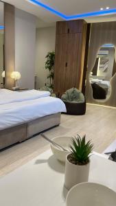 a bedroom with a bed and a table with a plant at Mfj Marbella Stay دخول ذاتي بموقف خاص وإطلالة مسبح in Al Khobar