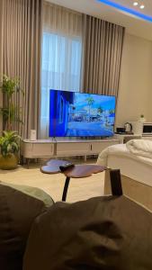 a living room with a flat screen tv and a bed at Mfj Marbella Stay دخول ذاتي بموقف خاص وإطلالة مسبح in Al Khobar