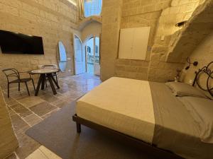 een slaapkamer met een bed, een tafel en een tv bij L'Incanto Caves in Matera