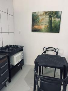 una cucina con piano cottura, forno a microonde e tavolo di Kitnets Ubatumirim a Ubatuba