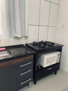 una cucina con fornelli e microonde su un bancone di Kitnets Ubatumirim a Ubatuba Altre 2 foto