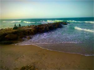 zwei Menschen stehen am Strand in der Nähe des Ozeans in der Unterkunft Casa 3 Quartos, 50 metros Da Praia in Cascavel + 3 Fotos