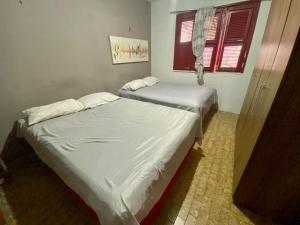 zwei Einzelbetten in einem Zimmer mit Fenster in der Unterkunft Casa 3 Quartos, 50 metros Da Praia in Cascavel