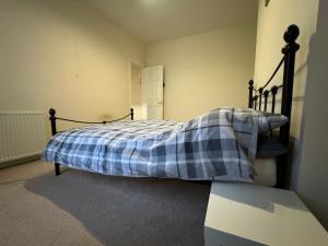 een slaapkamer met een bed met een geruite deken erop bij Sowerby Homes in Sowerby Bridge
