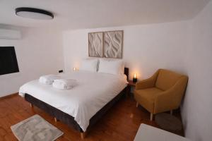 a bedroom with a white bed and a chair at One Apartments TLV in Tel Aviv