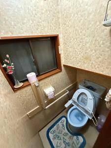 een kleine badkamer met een toilet en een raam bij 桜の家 in Saitama