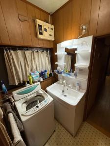 een kleine badkamer met een wasmachine en een wastafel bij 桜の家 in Saitama