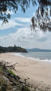 a view of a beach with a house in the distance at Omkar Homestay Adgaon Beach Sea View Next to Diveagar 2 in Adgaon