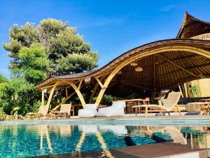 een resort met een zwembad met stoelen en een paviljoen bij Les Terrasses Ceningan in Nusa Lembongan