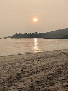 a beach with the sun rising over the water at Omkar Homestay Adgaon Beach Sea View Next to Diveagar 2 in Adgaon +4 photos