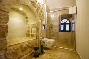 a stone bathroom with a shower and a toilet at Mara Loya Konağı in Mardin