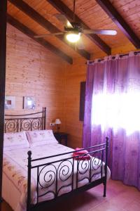 1 dormitorio con 1 cama y una ventana con cortinas moradas en La Casita de Madera, en Ardales