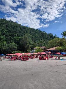 eine Gruppe von Menschen sitzt mit roten Sonnenschirmen an einem Strand in der Unterkunft Studio pé na areia Pereque - Açu in Ubatuba