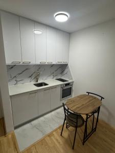 a kitchen with white cabinets and a table and a sink at Apartman "Paolo" Istočno Sarajevo in Vranješ +13 photos