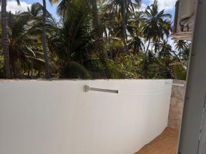 a white fence with palm trees in the background at Suite 05 em casa Beira mar, com ar condicionado , cozinha completa com Micro ondas air fryer forno elétrico fogão Geladeira freezer gelagua e cafeteira elétrica Tudo para vc se sentir em casa além de um Deck com churrasqueira vista mar in Icapuí +10 photos
