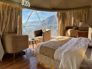 een slaapkamer met een bed en een groot raam bij Earthen Pods in Manāli