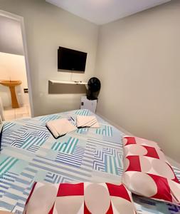 a bedroom with a bed with a tv on the wall at Sol Calor e Mar, achei minha pousada in Matinhos