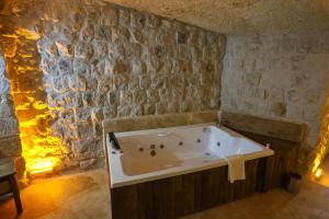 a bath tub in a room with a stone wall at Kayaharman cave otel in Nar +41 photos