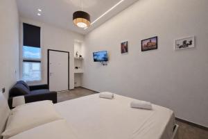 een witte slaapkamer met een bed en een stoel bij GemmaHouse in Casalecchio di Reno