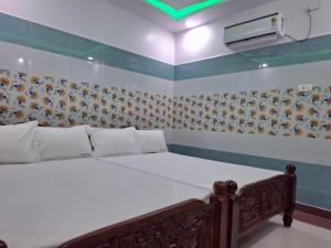 ein Bett in einem Zimmer mit Avertisementatronatronatronstrationstration in der Unterkunft Ambika Residency & Mahal in Tiruttani
