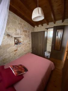 洛弗Lofitiko的卧室里有一张粉色大床，嵌在石墙里。