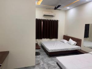 a room with two beds and a window at Maheshwari Homes in Ujjain +9 photos