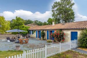 ein Haus mit einem weißen Zaun, einem Tisch und einem Sonnenschirm in der Unterkunft Gîtes de la Bernière in Brûlain