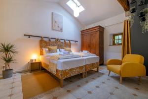 ein Schlafzimmer mit einem großen Bett und einem gelben Stuhl in der Unterkunft Gîtes de la Bernière in Brûlain