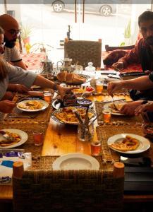 een groep mensen die rond een tafel pizza eten bij Imsouane Sea surf Family in Imsouane